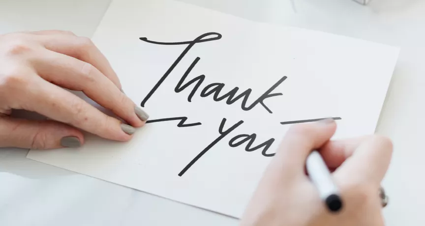 Person writing a thank you note
