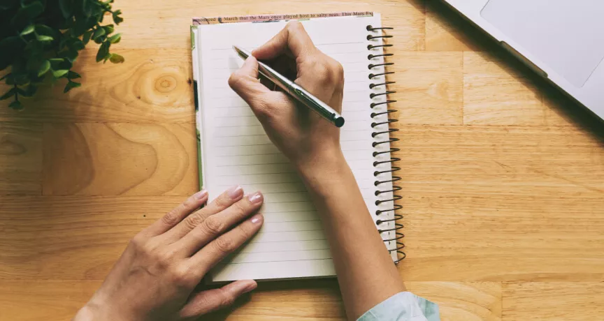 A person writing a note in a journal