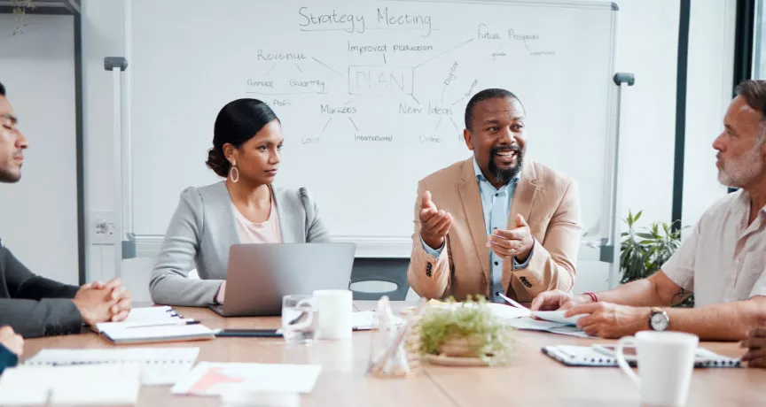Coworkers sitting around a table with the focus on a one employee in the middle