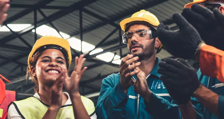 A photograph of construction workers clapping in a circle
