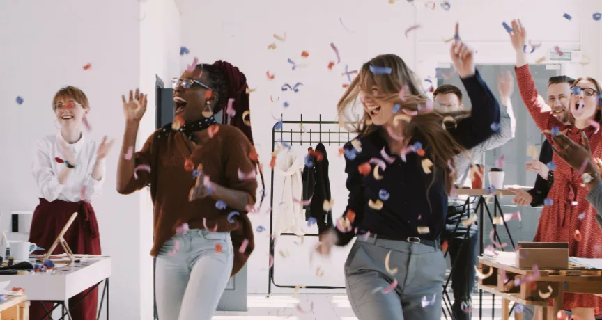A team celebrating at work with confetti falling down in the background