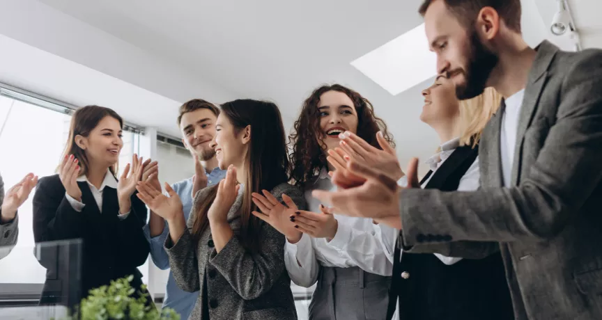 A group of employees cheering around a table