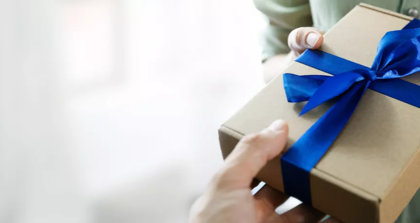 Image shows a person handing a gift to another person