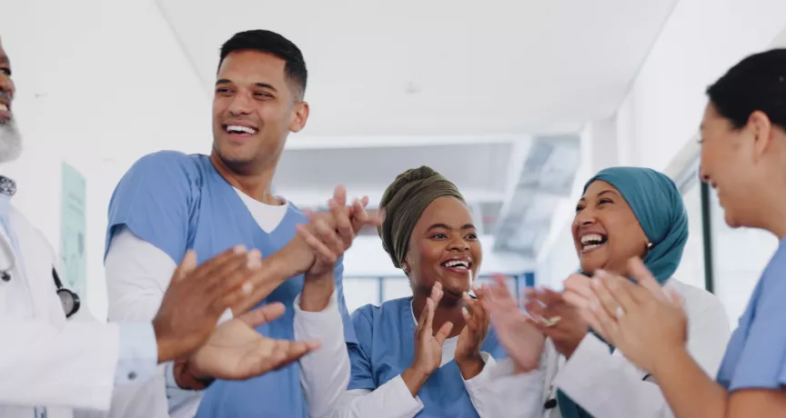 Three nurses and doctors celebrating by clapping their hands