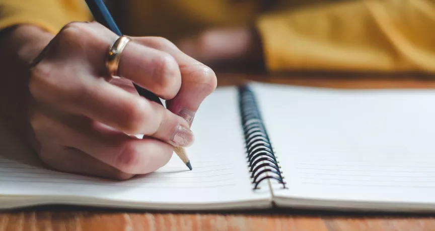 Image shows a close up of a person writing a message