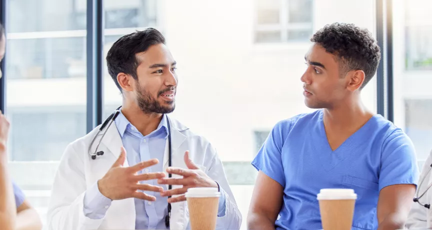 Two doctors and two nurses chatting at a table with coffee