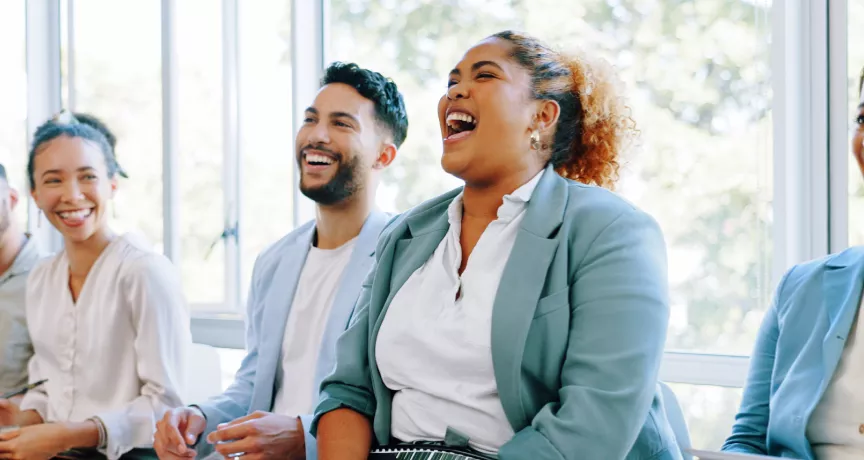 Five employees sitting down laughing on a couch together