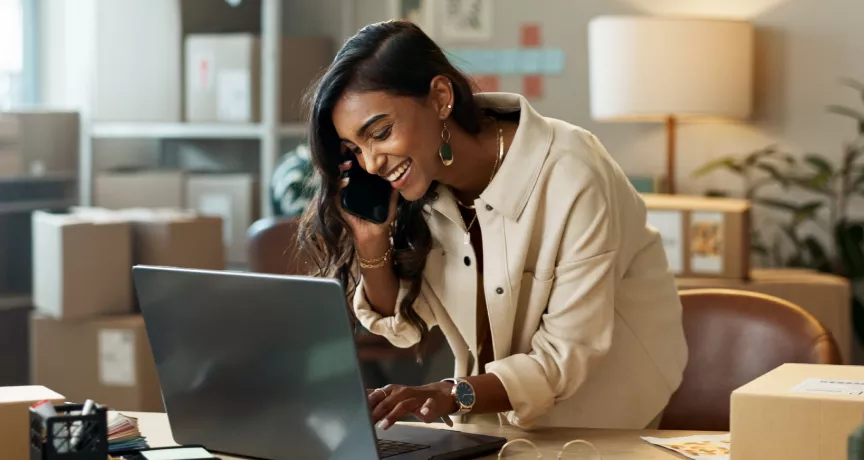 Image shows a woman looking down at her computer and smiling