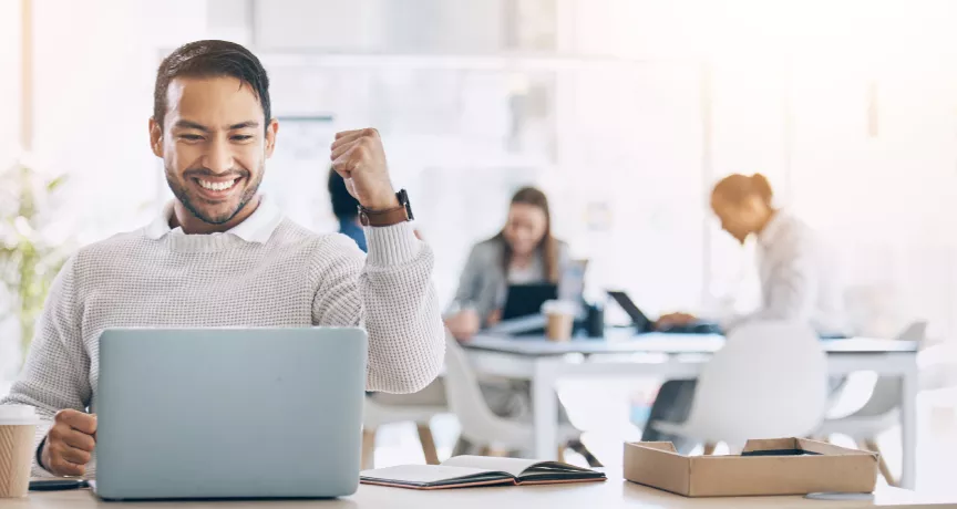 Image shows an employee celebrating by their computer.