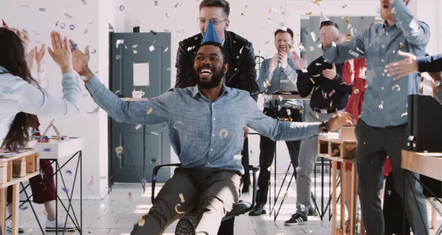 Image shows a person celebrating at an office party