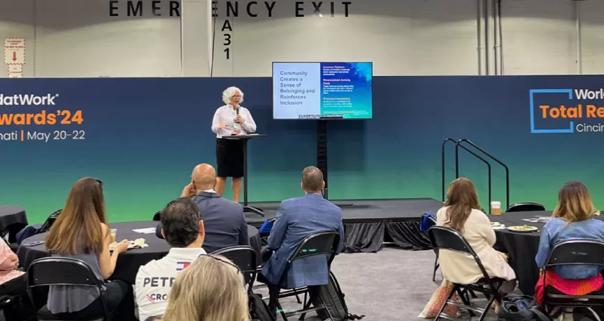 Image shows Theresa Harkins-Schulz, Inspirus SVP of Product and Customer Experience, speaking at the Total Rewards conference in front of attendees.