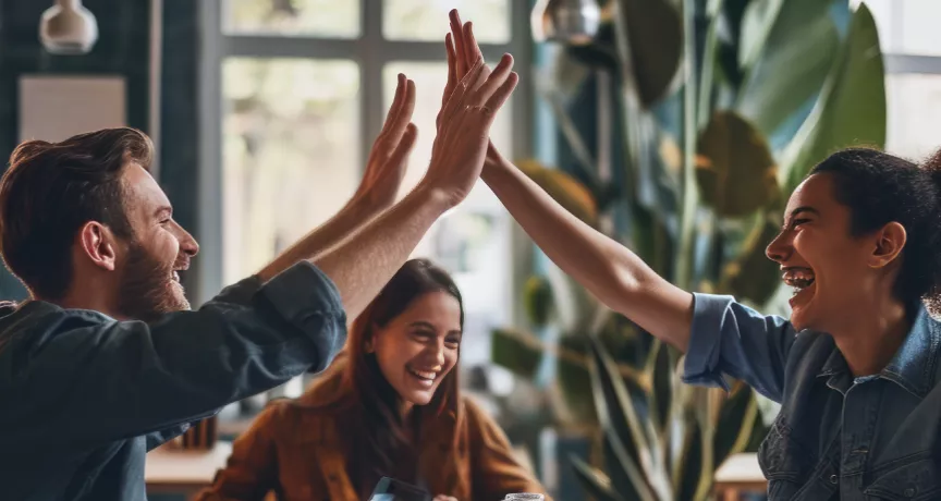 Shows two co-workers high fiving over a table