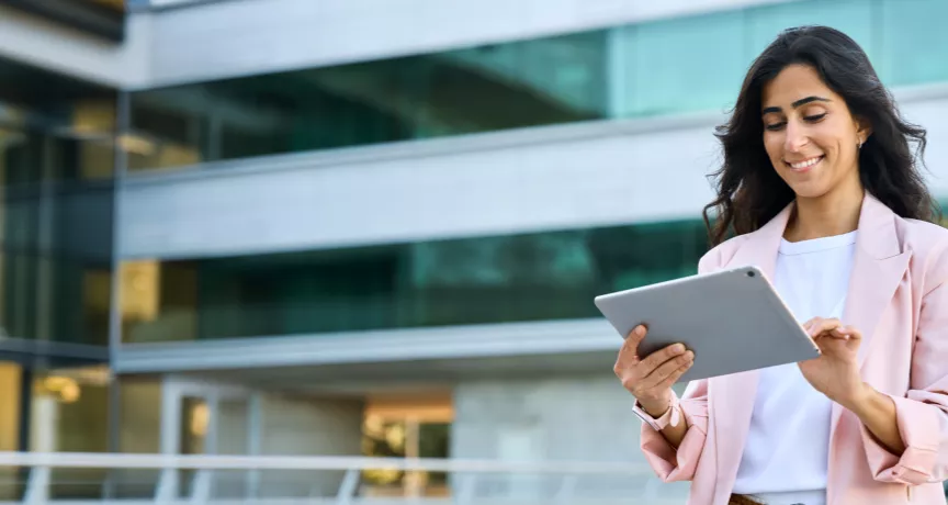 A woman in business clothes smiling down at her tablet
