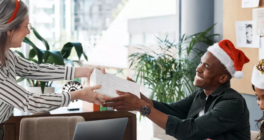 An employee giving their co-worker a holiday gift for appreciation