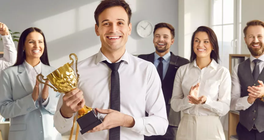 An employee holding an award trophy in front of their colleagues