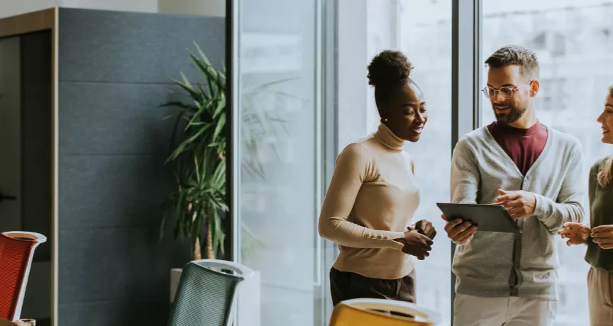 A group of employees working collaboratively together on an tablet.