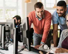 Three employees gathered around a computer