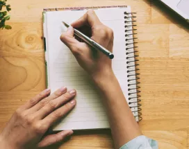 A person writing a note in a journal