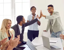 Two employees high fiving over a table