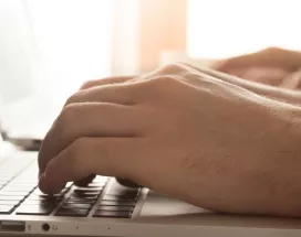 Image shows a close up of a person typing on their laptop