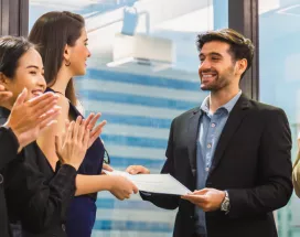 Image shows an employee receiving a certificate in front of a group of employees.