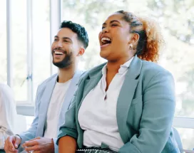 Five employees sitting down laughing on a couch together
