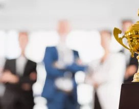 Image shows a trophy sitting in front of a group of employees