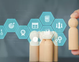 Image shows a person moving a wooden figure with various business symbols in front
