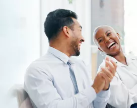 Image shows two employees laughing together along with two others in the background.