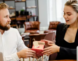 Image shows one employee giving a gift to another employee.