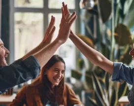 Shows two co-workers high fiving over a table