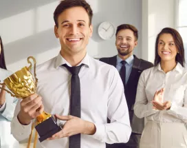An employee holding an award trophy in front of their colleagues