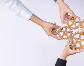 A group of employees creating a cogwheel with each holding a small cog