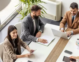 An image of a leadership team going over ways to create a healthy company culture and positive work culture to recognize employees and contribute to business success. They are discussing team building activities to integrate new employees into the organization's culture to create a positive environment and overall thriving culture.