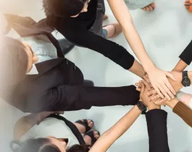 A group of employees huddled together with their hands stacked together.