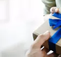 Image shows a person handing a gift to another person