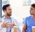 Two doctors and two nurses chatting at a table with coffee