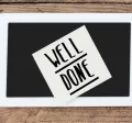 Image shows a sticky note on a desk that says "Well Done"