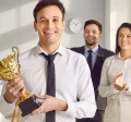 An employee holding an award trophy in front of their colleagues