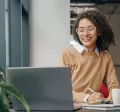Employee smiling as they communicate at work on their laptop