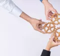 A group of employees creating a cogwheel with each holding a small cog