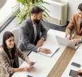 An image of a leadership team going over ways to create a healthy company culture and positive work culture to recognize employees and contribute to business success. They are discussing team building activities to integrate new employees into the organization's culture to create a positive environment and overall thriving culture.