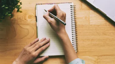 A person writing a note in a journal