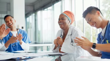 A small group of healthcare workers laughing and smiling at a table