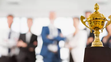 Image shows a trophy sitting in front of a group of employees