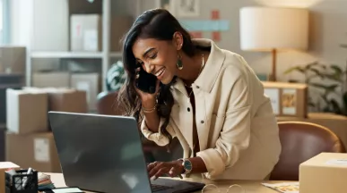 Image shows a woman looking down at her computer and smiling