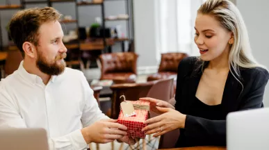 Image shows one employee giving a gift to another employee.