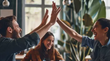 Shows two co-workers high fiving over a table
