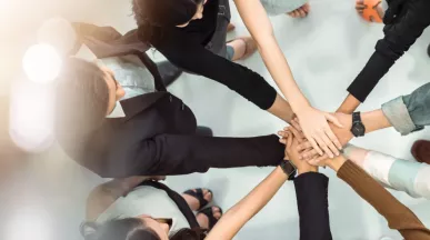 A group of employees huddled together with their hands stacked together.