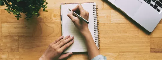 A person writing a note in a journal